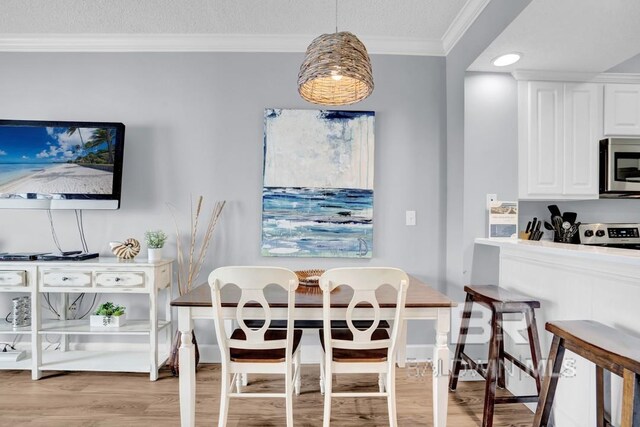 22984 Perdido Beach Blvd Unit 52D, Orange Beach, AL 36561 - dining space featuring a textured ceiling, light wood-style floors, and ornamental molding