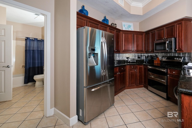 kitchen with stainless steel appliances, backsplash, crown molding, dark stone counters, and light tile patterned floors