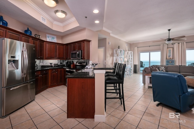 kitchen with a kitchen bar, crown molding, tasteful backsplash, and appliances with stainless steel finishes