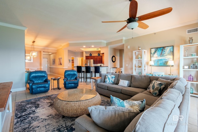 tiled living room with ceiling fan with notable chandelier and ornamental molding