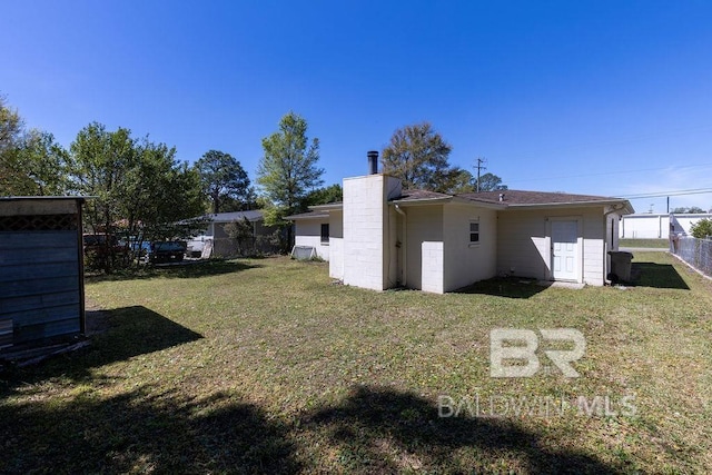 rear view of house with a yard, fence, and a chimney