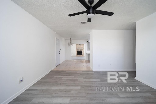 unfurnished room with visible vents, ceiling fan with notable chandelier, a textured ceiling, and wood finished floors