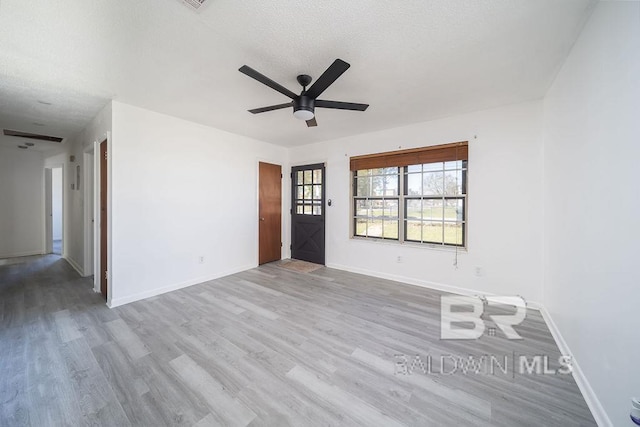 unfurnished room featuring ceiling fan, baseboards, a textured ceiling, and wood finished floors