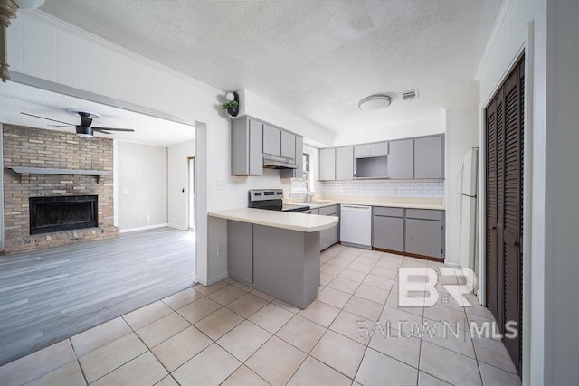 kitchen featuring gray cabinets, white appliances, light tile patterned flooring, and a peninsula