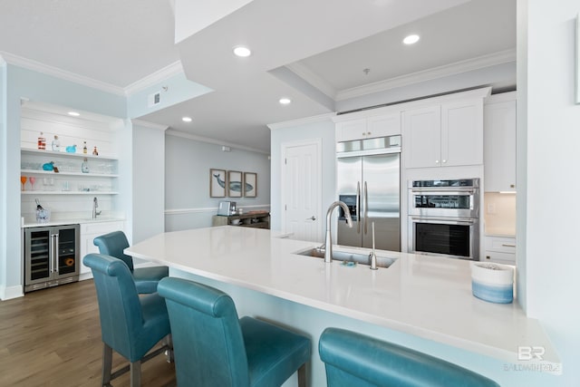 kitchen with wine cooler, crown molding, recessed lighting, appliances with stainless steel finishes, and a sink