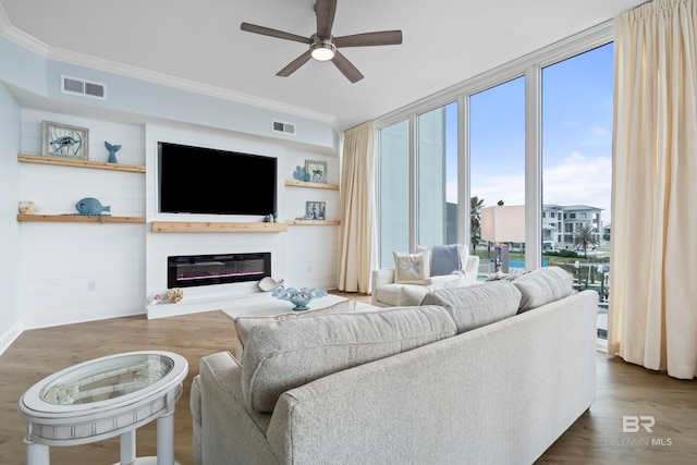28250 Canal Rd Unit 101, Orange Beach, AL 36561 - living room featuring a glass covered fireplace, visible vents, crown molding, and wood finished floors