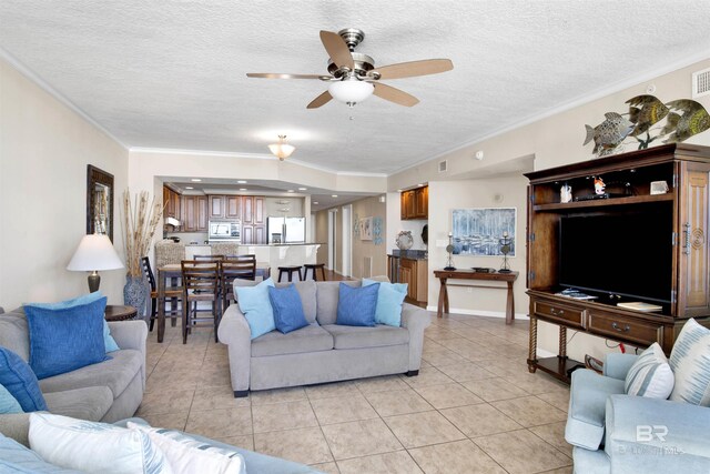 living room with ceiling fan, light tile patterned floors, crown molding, and a textured ceiling