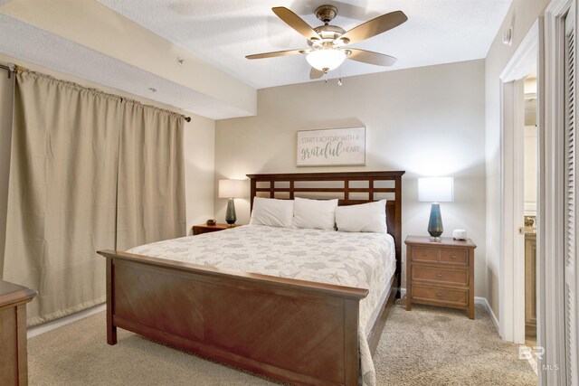 bedroom with ceiling fan, light colored carpet, and a textured ceiling