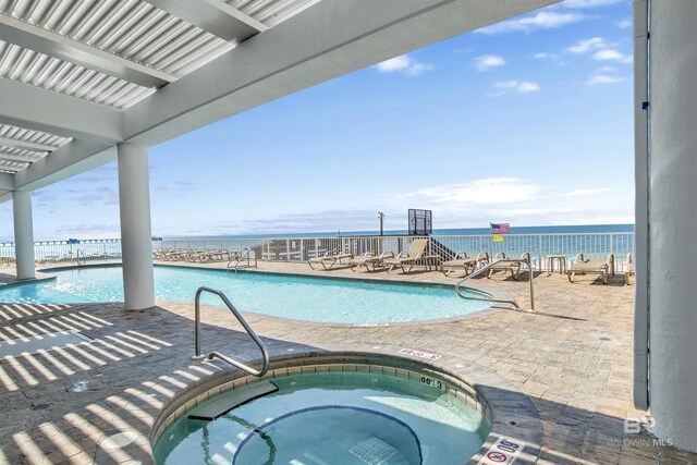 view of pool featuring a hot tub and a water view