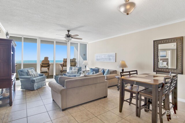 tiled living room with ceiling fan, crown molding, a water view, and a textured ceiling