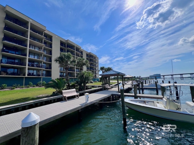 view of dock with a balcony, a gazebo, and a water view