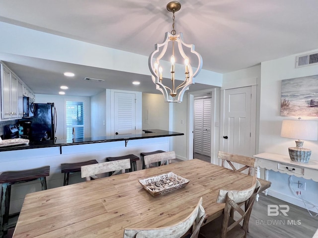 dining space with sink, an inviting chandelier, and hardwood / wood-style flooring