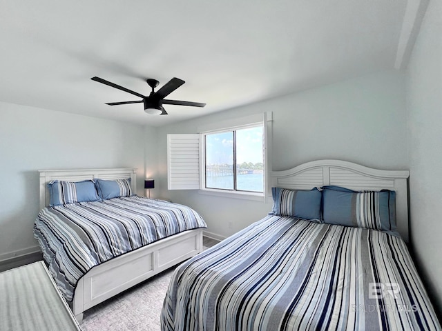 bedroom featuring ceiling fan and a water view