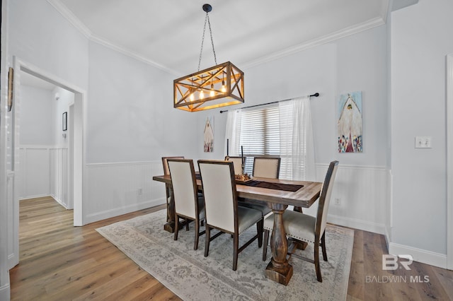 dining area featuring crown molding, wood finished floors, and a wainscoted wall