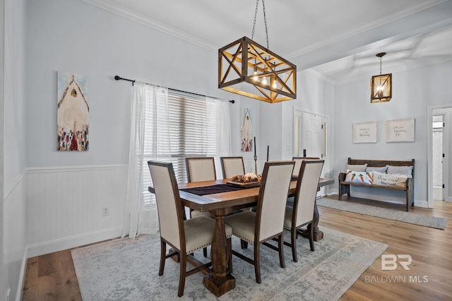 dining room with crown molding, wood finished floors, and a wainscoted wall