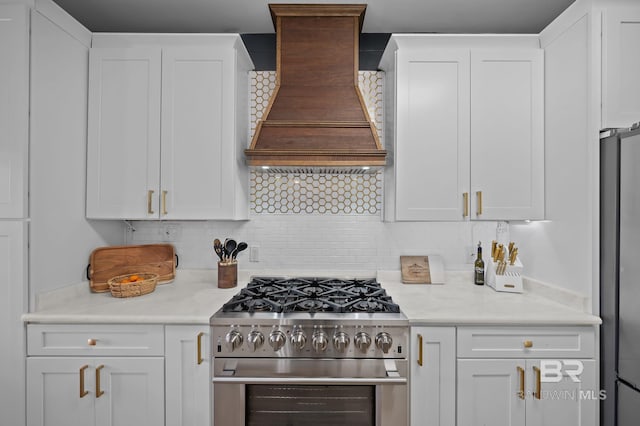 kitchen featuring premium range hood, appliances with stainless steel finishes, white cabinets, and light countertops