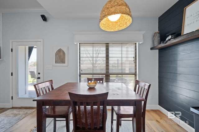 dining area with wooden walls, a healthy amount of sunlight, and light wood finished floors