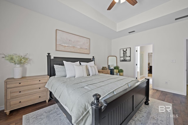 bedroom with visible vents, a raised ceiling, dark wood-type flooring, and baseboards