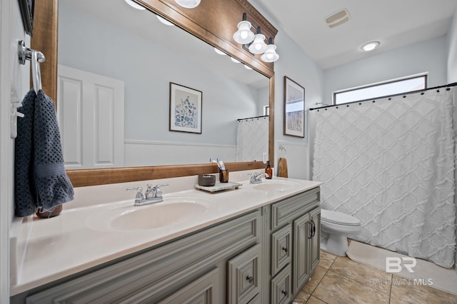 full bathroom featuring a wainscoted wall, toilet, visible vents, and a sink