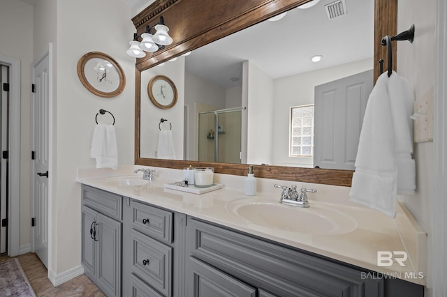 bathroom featuring double vanity, visible vents, a stall shower, and a sink