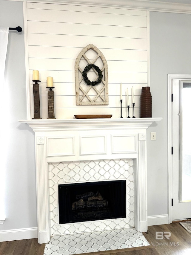 interior details with baseboards, wood finished floors, and a tile fireplace