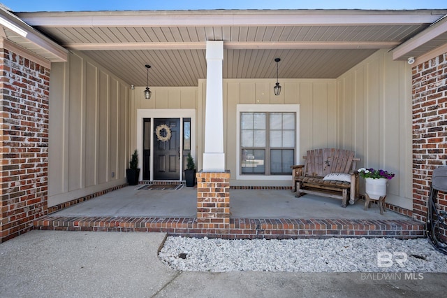 doorway to property with covered porch and brick siding