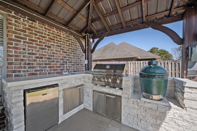 view of patio featuring a gazebo, grilling area, exterior kitchen, and fence