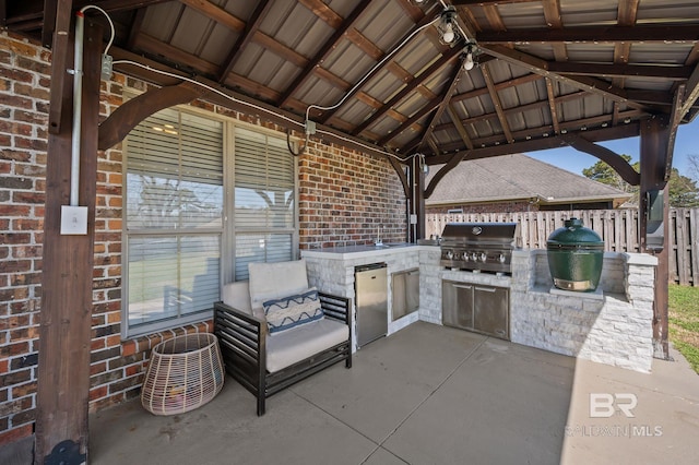 view of patio / terrace featuring a gazebo, grilling area, an outdoor kitchen, and fence