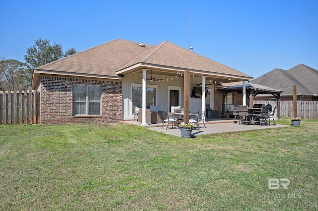 rear view of house featuring a patio, fence, roof with shingles, ceiling fan, and brick siding