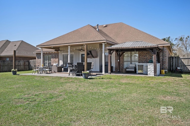 rear view of house with a gazebo, a lawn, brick siding, and a fenced backyard