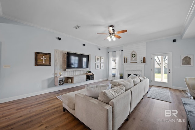 living area featuring baseboards, wood finished floors, and crown molding