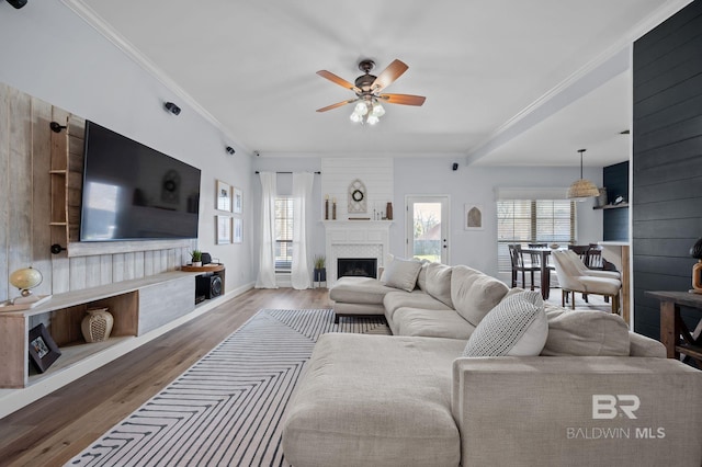 living room with a wealth of natural light, wood finished floors, a fireplace, and ornamental molding