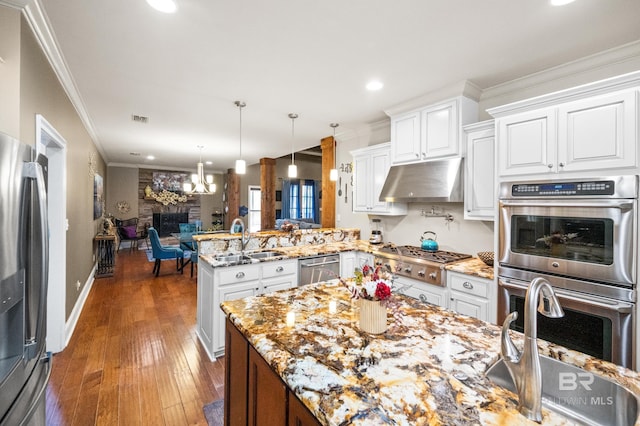 kitchen featuring sink, white cabinetry, hanging light fixtures, stainless steel appliances, and kitchen peninsula