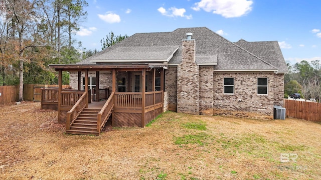 back of house with a deck, a lawn, and central air condition unit