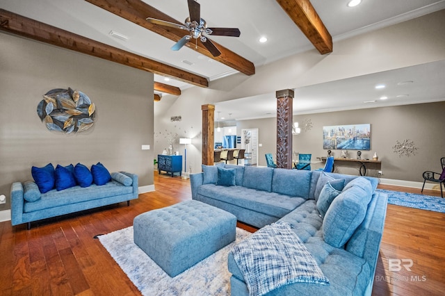 living room featuring ornate columns, beamed ceiling, ceiling fan, crown molding, and dark wood-type flooring