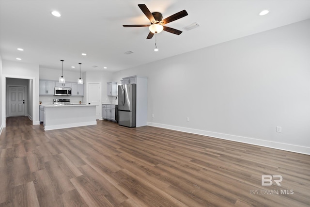 unfurnished living room featuring dark wood-type flooring and ceiling fan