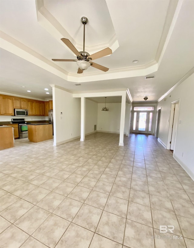 unfurnished living room featuring light tile patterned flooring, decorative columns, ceiling fan, a tray ceiling, and crown molding