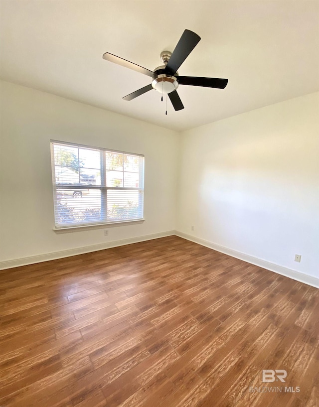 spare room with dark wood-type flooring and ceiling fan