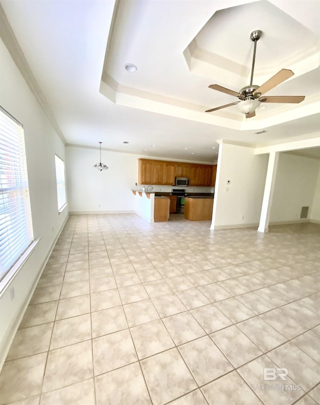 unfurnished living room featuring ornamental molding, a raised ceiling, ceiling fan with notable chandelier, and light tile patterned floors