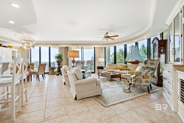 tiled living room with expansive windows, ceiling fan, ornamental molding, and a raised ceiling