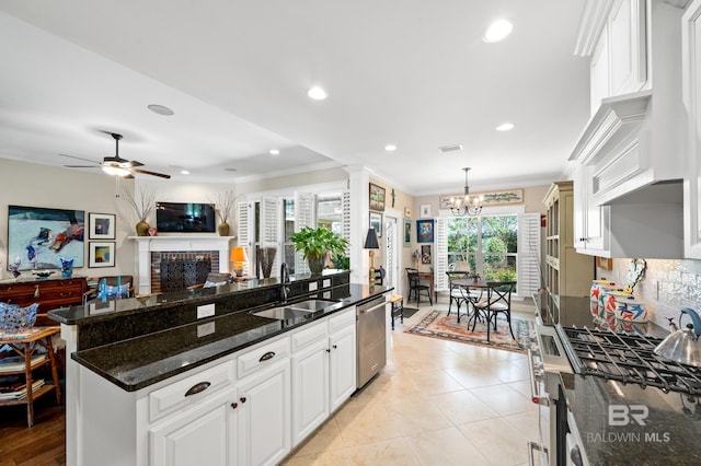 kitchen featuring white cabinets, a brick fireplace, decorative light fixtures, dishwasher, and ceiling fan with notable chandelier