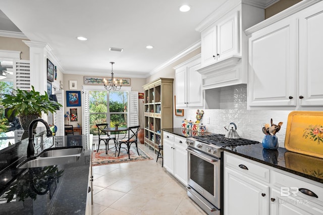 kitchen with white cabinets, sink, high end stove, dark stone countertops, and crown molding