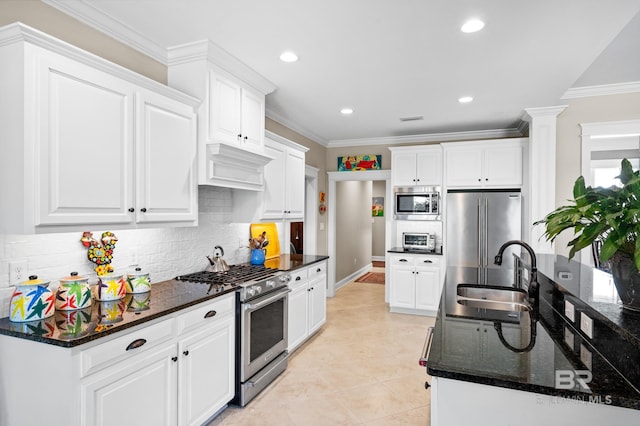 kitchen featuring dark stone countertops, sink, high end appliances, and white cabinetry