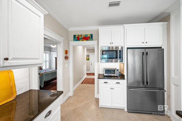 kitchen featuring dark stone countertops, white cabinets, stainless steel appliances, and crown molding