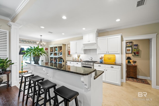 kitchen with high end range, light hardwood / wood-style flooring, ornamental molding, and white cabinetry