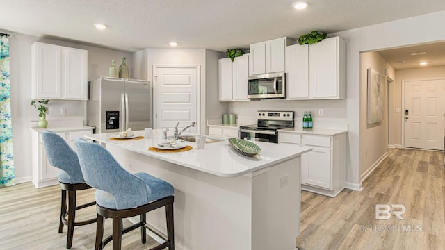 1040 Hayward Loop, Foley, AL 36535 - kitchen featuring appliances with stainless steel finishes, a breakfast bar, light wood-type flooring, white cabinetry, and recessed lighting