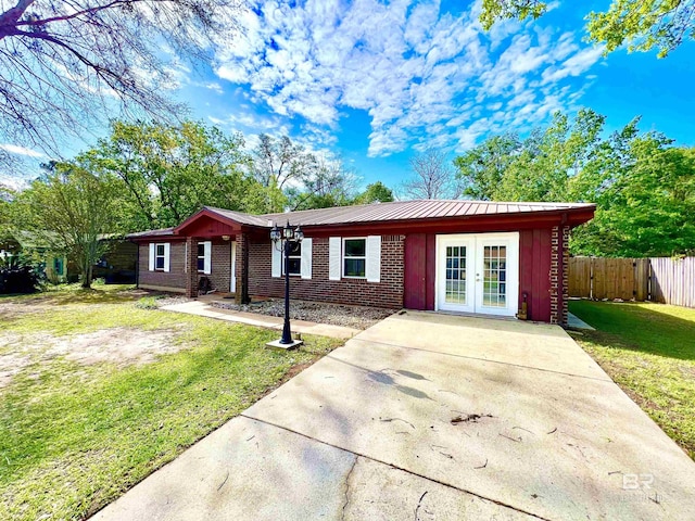 ranch-style home with french doors, fence, a front lawn, and brick siding