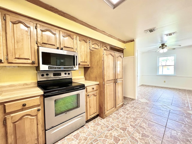 kitchen featuring baseboards, visible vents, ceiling fan, stone finish flooring, and appliances with stainless steel finishes