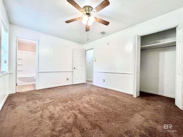 unfurnished bedroom with ceiling fan, ensuite bathroom, a closet, and dark colored carpet