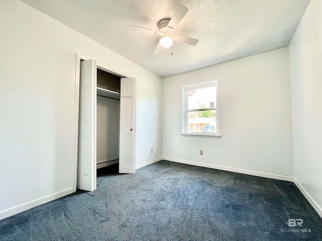 unfurnished bedroom featuring dark carpet, a closet, ceiling fan, and a textured ceiling